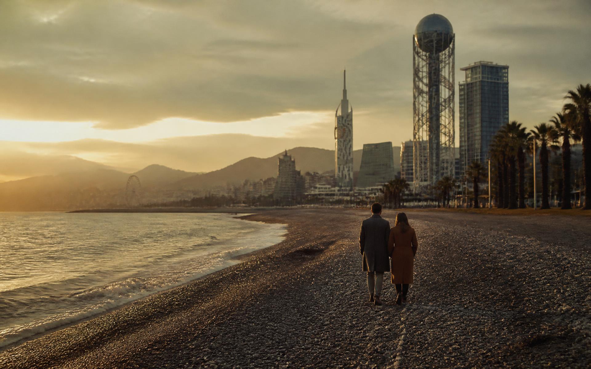 Couple walking along the Black Sea shoreline in Batumi at golden hour